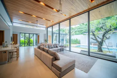 a living room with a large couch and glass windows at Botanica Foresta 4BR Luxury Villa with Pool by NLA in Bang Tao Beach