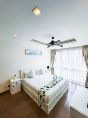 a white bedroom with a bed and a ceiling fan at Townhouse in Laguna Park in Phuket Town