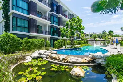 a hotel with a pond in front of a building at The Title Seaview Apartment in Phuket Town
