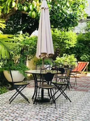 a table and chairs with an umbrella on a patio at Guest House, shared pool, private bathroom and kitchen in Phuket Town