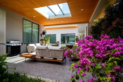 a patio with a couch and some purple flowers at Villa Mimosa 3, Luxury 4Bedroom Private Pool-Rawai in Kata Beach