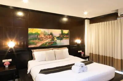 a bedroom with a large bed with two towels at Best Venue Hotel in Patong Beach