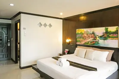 a bedroom with a large bed with a painting on the wall at Best Venue Hotel in Patong Beach