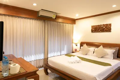 a bedroom with a bed and a table and a television at Best Venue Hotel in Patong Beach