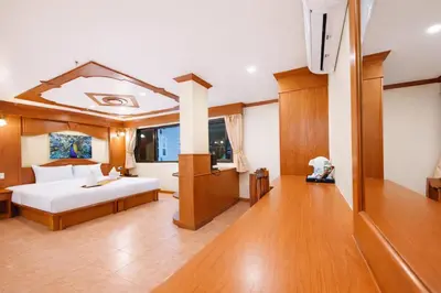 a bedroom with a bed in a room with wooden floors at Tiger Complex Hotel in Patong Beach