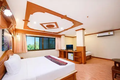 a bedroom with a bed and a desk and a window at Tiger Complex Hotel in Patong Beach