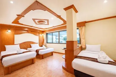 a room with three beds and a large window at Tiger Complex Hotel in Patong Beach