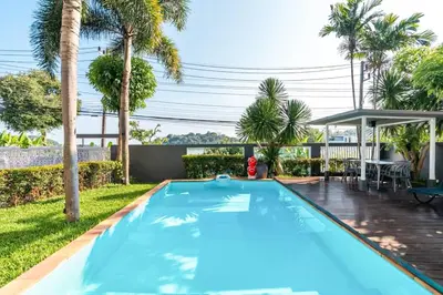a blue swimming pool in a backyard with palm trees at Poolvillapanwa in Panwa Beach