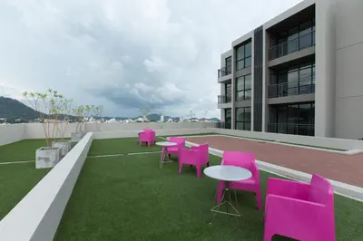 a patio with pink chairs and tables on the roof of a building at Sugar Palm Residence in Phuket Town