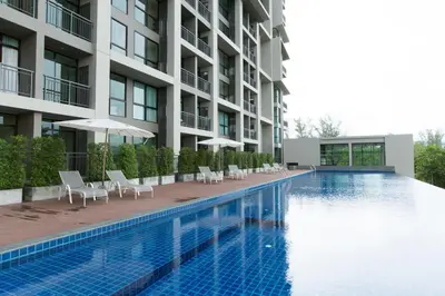 a swimming pool with chairs and umbrellas next to a building at Sugar Palm Residence in Phuket Town