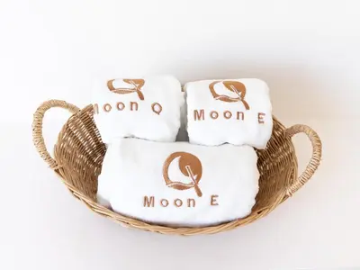 a basket of towels with the monogrammed towels at MoonE in Karon Beach