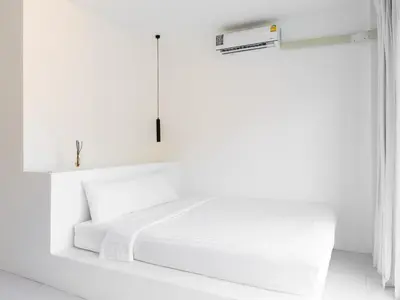 a white bedroom with a white bed and a box at MoonE in Karon Beach