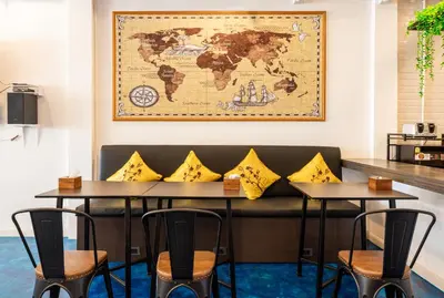 a seating area with two tables and a map on the wall at Marco Polo Phuket Poshtel & Bistro in Phuket Town