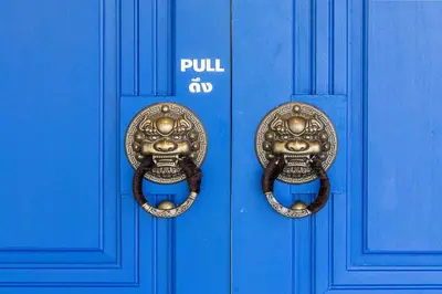 a blue door with a pair of gold door handles at Marco Polo Phuket Poshtel & Bistro in Phuket Town