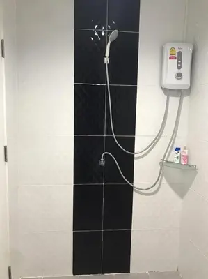 a shower in a bathroom with a black and white tile wall at Rest Mind House in Surin Beach