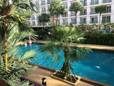 a swimming pool with a palm tree in front of a building at Phuket Villa Patong- Pool View in Patong Beach