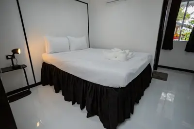 a bedroom with a bed with a black skirt at The Bright House, Koh Phi Phi in Phi Phi Don