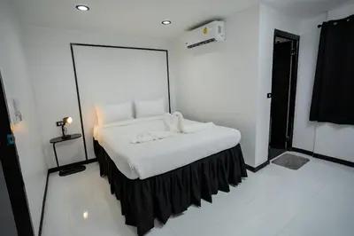 a bedroom with a bed with white sheets and a mirror at The Bright House, Koh Phi Phi in Phi Phi Don