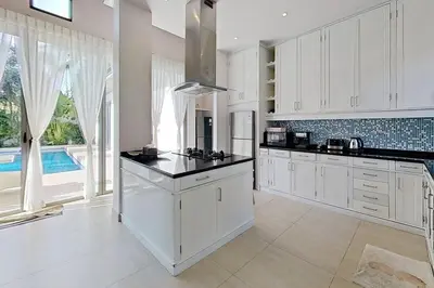 a kitchen with white cabinets and a large window at Mandala by Villacarte in Bang Tao Beach