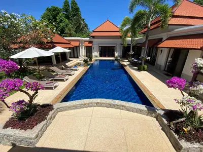 a swimming pool in a resort with lounge chairs and flowers at Luxury Sai Taan Villa in Bang Tao in Bang Tao Beach