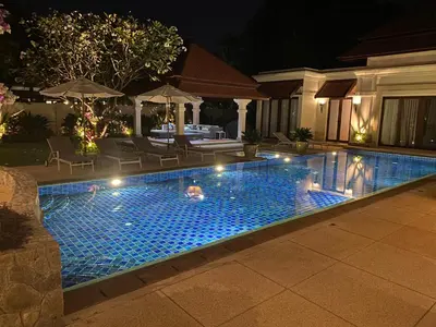 a swimming pool with lights in a backyard at night at Luxury Sai Taan Villa in Bang Tao in Bang Tao Beach