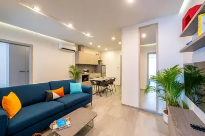 a living room with a blue couch and a kitchen at HOMA Cherngtalay Phuket in Bang Tao Beach