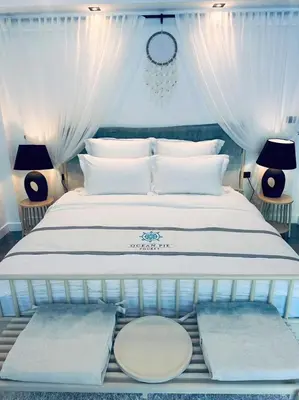 a bedroom with a large white bed with white curtains at Ocean Pie Phuket - Adult Only in Rawai Beach