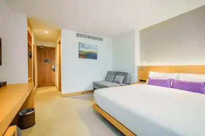 a bedroom with a large white bed and a chair at The Lunar Patong in Patong Beach