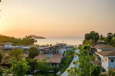 a view of houses and the ocean at sunset at Artisan koh yao yai handcraft beachfront villas. in Ban Lo Pa Ret