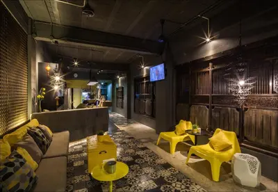 a lobby with a couch and tables and yellow chairs at Fulfill Phuket - SHA in Phuket Town