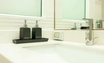 a bathroom with a sink with two soap dispensers on it at Rudi Condo by Q Conzept in Kata Beach