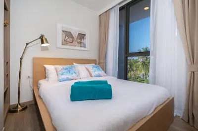 a bedroom with a large white bed with a window at Apartment in laguna , 600 metres from the beach in Phuket Town