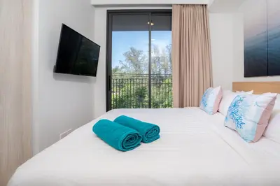 a bedroom with a white bed with blue pillows on it at Apartment in laguna , 600 metres from the beach in Phuket Town