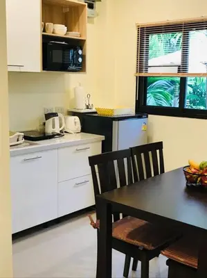 a kitchen with white cabinets and a table and chairs at Summer House,shared pool, private bathroom and kitchen in Ban Phlu Yai