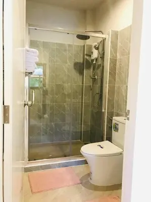 a bathroom with a shower with a toilet and a glass door at Summer House,shared pool, private bathroom and kitchen in Ban Phlu Yai