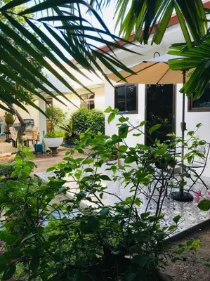 a house with an umbrella and a yard with plants at Summer House,shared pool, private bathroom and kitchen in Ban Phlu Yai