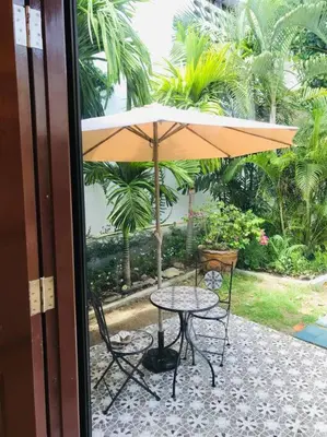 a table and chairs with an umbrella on a patio at Summer House,shared pool, private bathroom and kitchen in Ban Phlu Yai