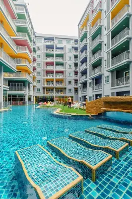 a swimming pool with chaise lounges in front of apartment buildings at Elite Suites Patong in Patong Beach