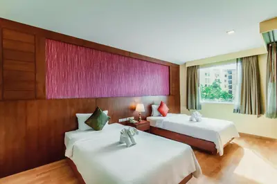 a hotel room with two beds and a window at Elite Suites Patong in Patong Beach