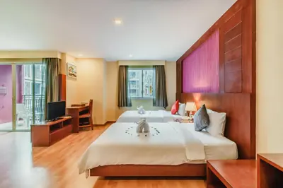 a hotel room with a large bed and a television at Elite Suites Patong in Patong Beach