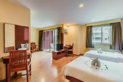 a hotel room with two beds and a television at Elite Suites Patong in Patong Beach