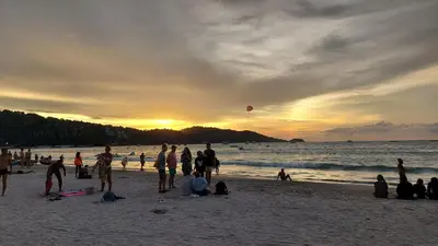 a group of people on the beach at sunset at Sawasdee Apartment Patong in Patong Beach