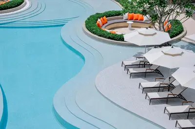 a pool with chairs and umbrellas next to a swimming pool at Laya Resort Phuket in Layan Beach