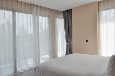 a bedroom with a bed and a large window at Laya Resort Phuket in Layan Beach
