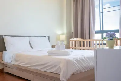 a bedroom with a white bed with towels on it at The Lago Apartments in Ban Suan