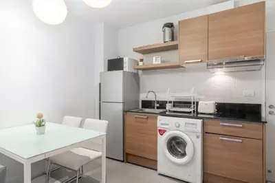 a kitchen with a washing machine and a table at The Lago Apartments in Ban Suan