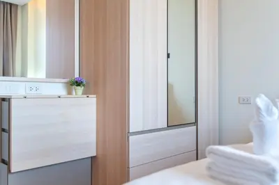 a bathroom with a wooden closet with a mirror at The Lago Apartments in Ban Suan