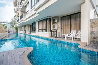 a swimming pool in front of a building at The Lago Apartments in Ban Suan