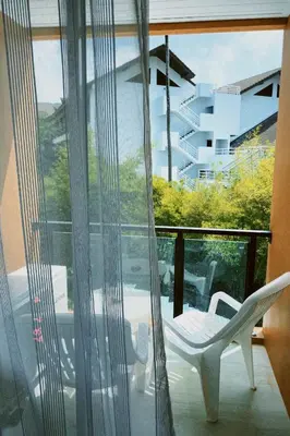 a room with a window with a chair on a balcony at Sasimanta in Kamala Beach
