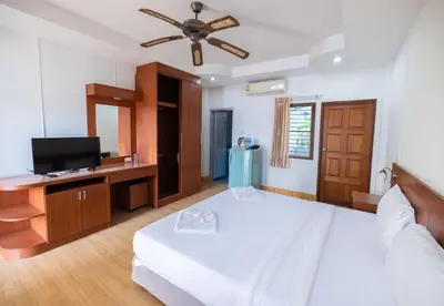 a bedroom with a bed and a flat screen tv at G house guest house in Patong Beach
